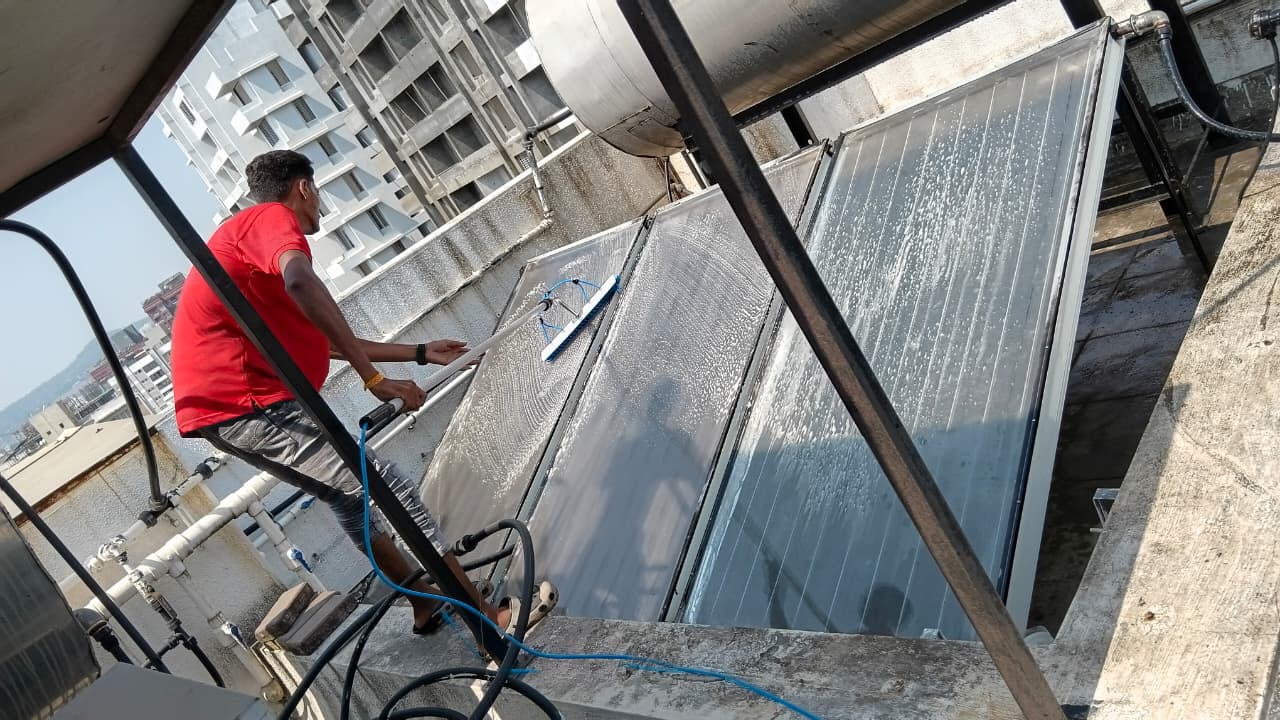 Technician cleaning glazed flat-plate solar water heater collectors