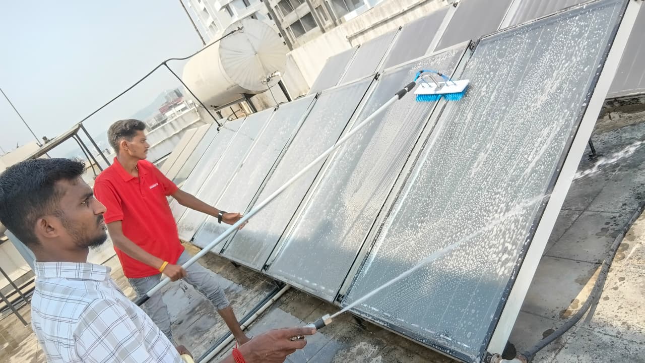 Two technicians cleaning commercial solar water heater collector bank