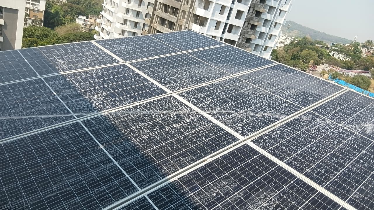 Technician applying water spray across 20 kW solar panels